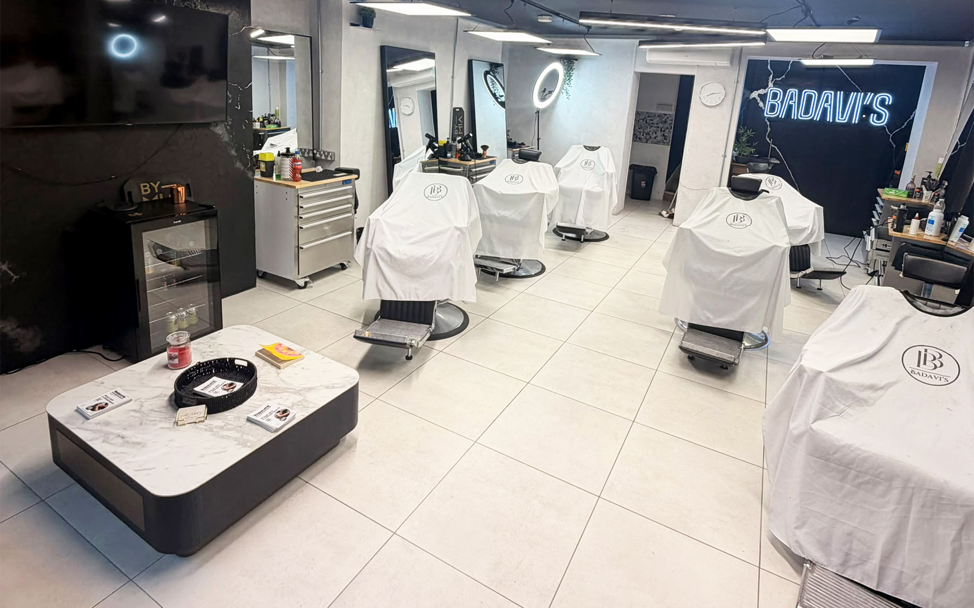 Inside Badavi's Barbershop, with barber chairs and the illuminated Badavi's sign